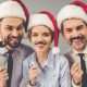 Karriere auf Weihnachtsfeier fördern drei Mitarbeiter vor Fotobox und mit Weihnachtsmützen
